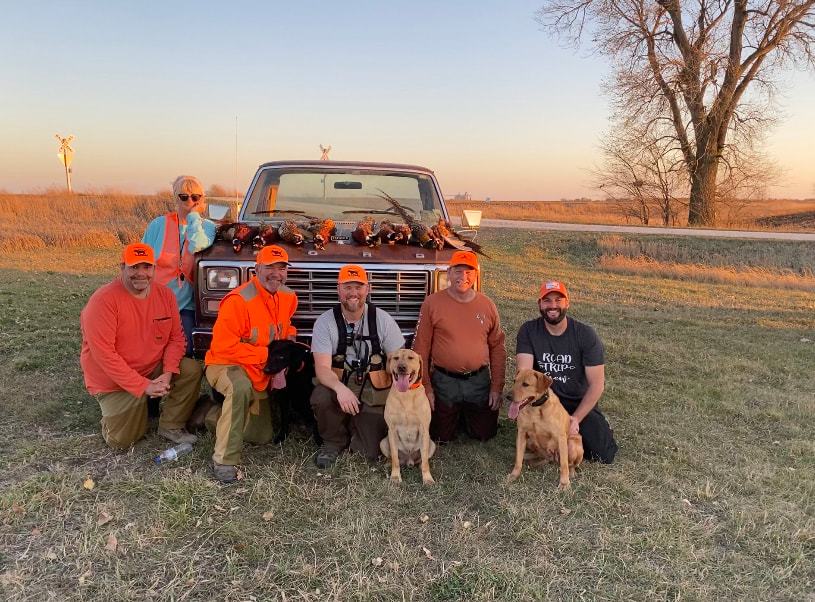 hunting party with pheasants on truck hood and dogs
